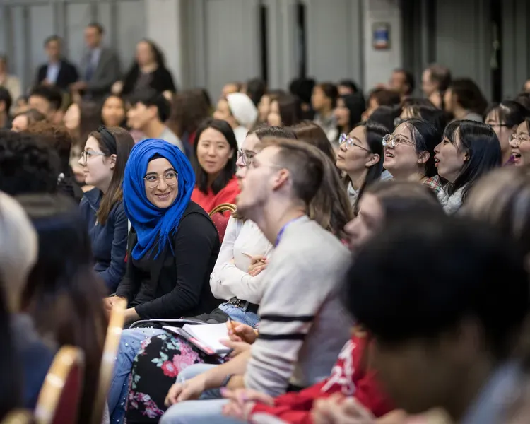 a group of students discuss something while others look at a screen