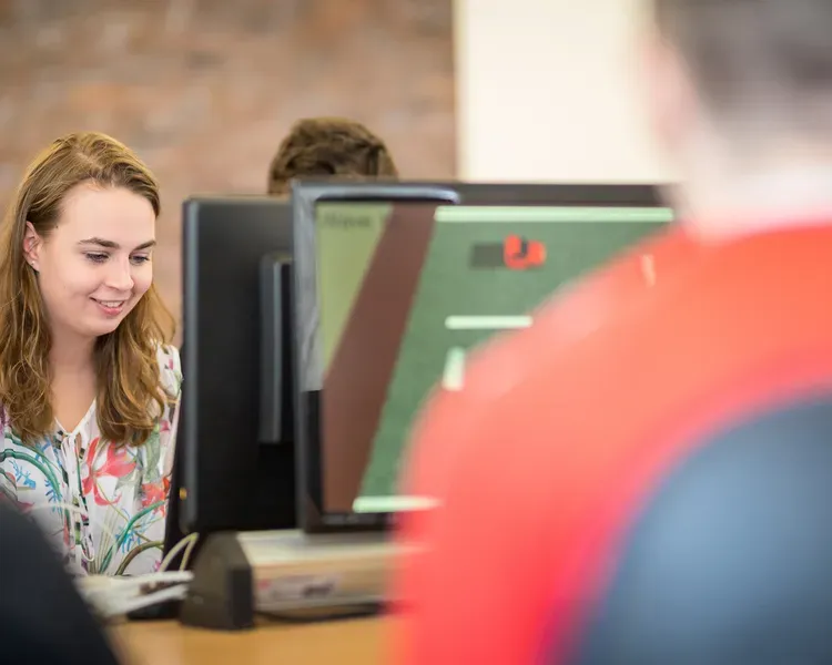 Students working on computers around a desk