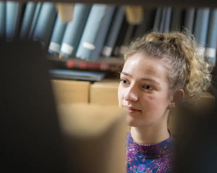 Girl looking at old books in an archive