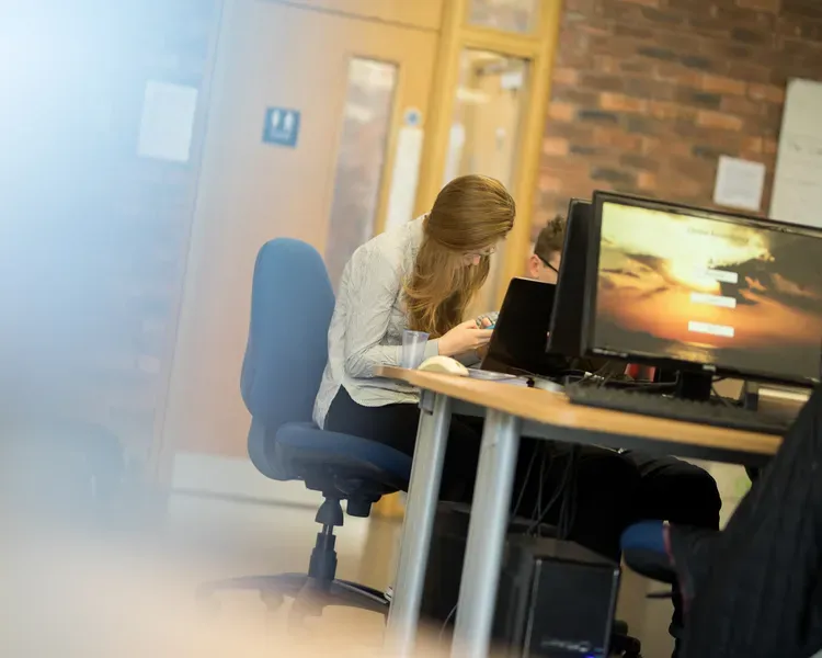a person sitting on a blue chair and a computer screen
