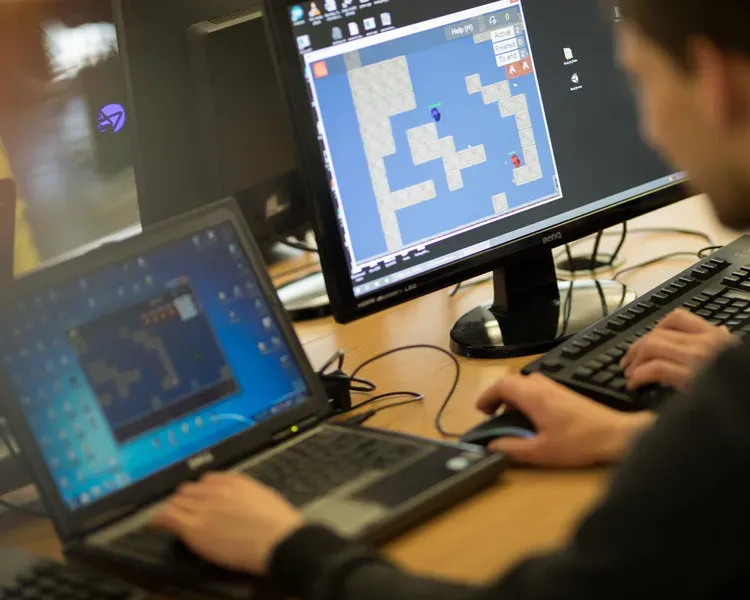 a person on a laptop playing a game that is showing on the screen