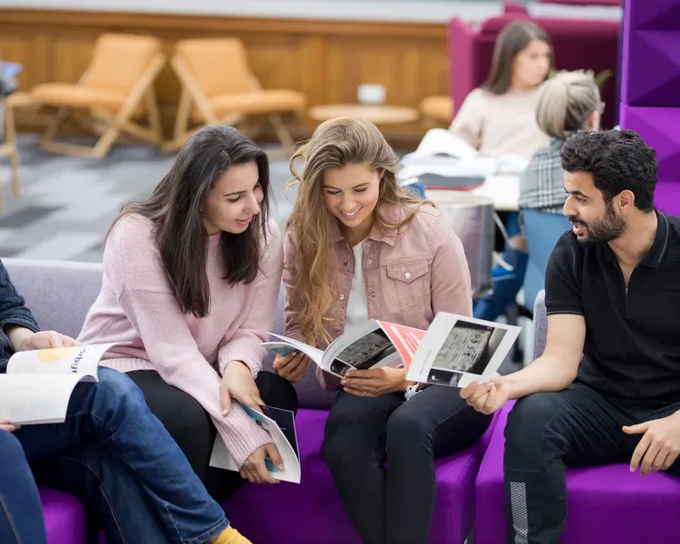 Students in social sciences sitting on purple sofas and reading books