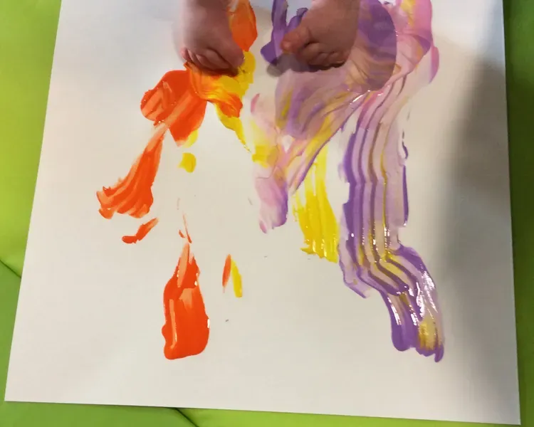 Baby painting with their feet on the floor