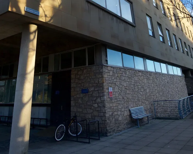 a building entrance with a ramp. There is also a bike and a bench