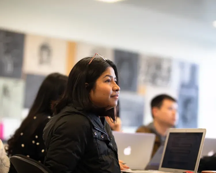 Student sitting with laptop listening to lecture
