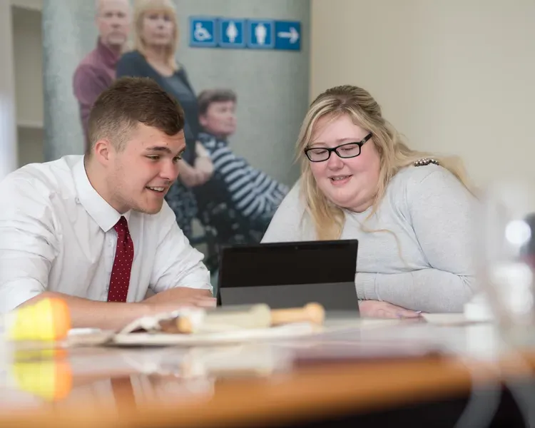 two students sitting around a laptop