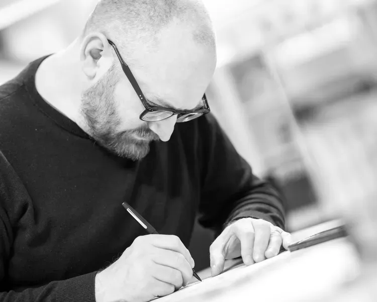 Mature male student writing or sketching with a pencil