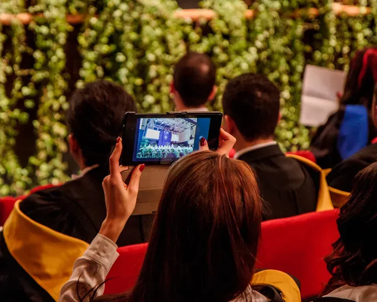 a graduate taking a photo of the ceremony on a tablet