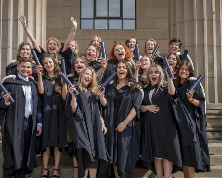a group of graduates in gowns holding their certificates 