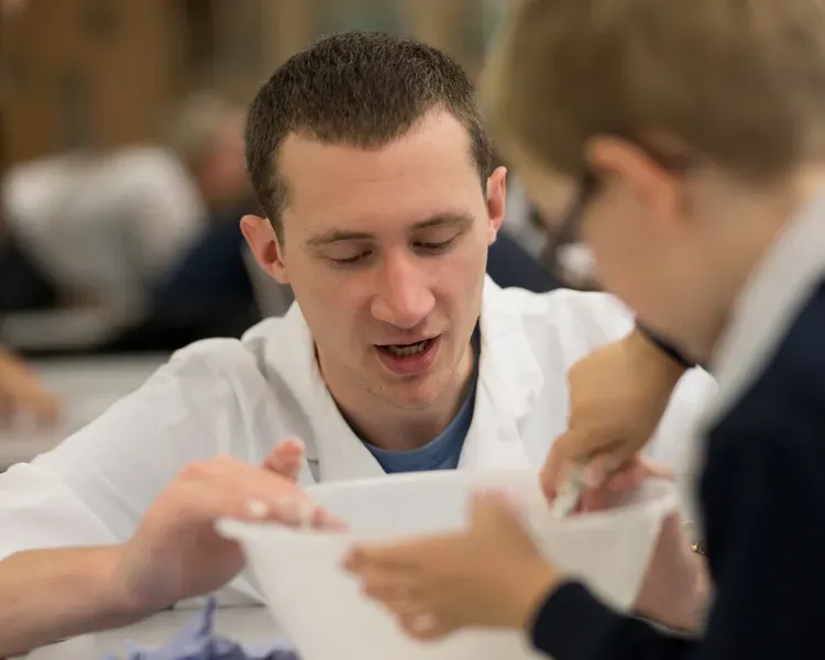 boy with a male student helping put something in a mixing bowl