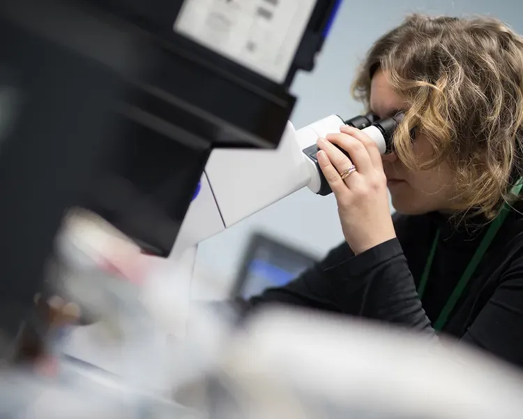 a woman looks into a microscope