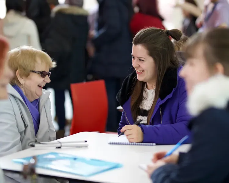 an older woman talking and laughing with a younger woman
