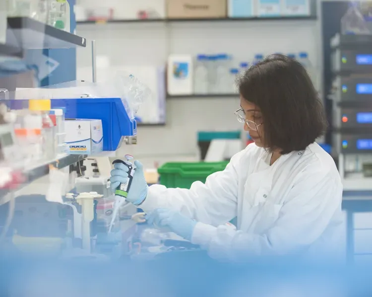 Scientist using syringe to fill up container in lab