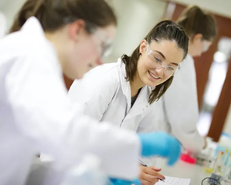 students in lab coats working side by side in a lab