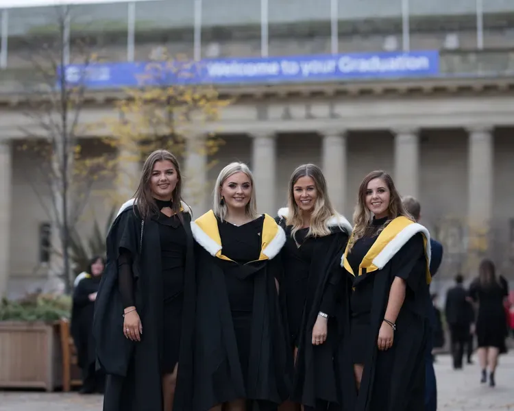 Four graduate students standing in front of Caird Hall Dundee for Winter graduation