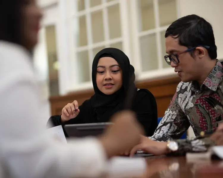 A couple of students sitting around a table looking at a laptop