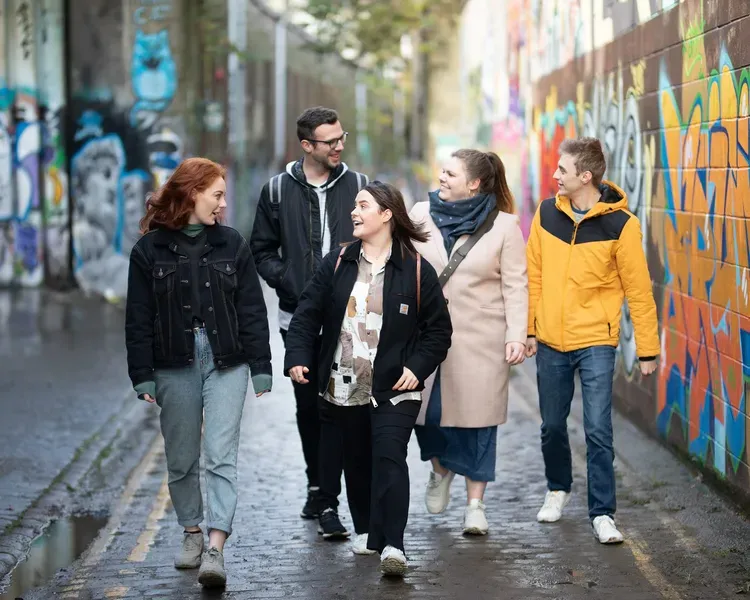 Students walking beside graffiti in Dundee city centre