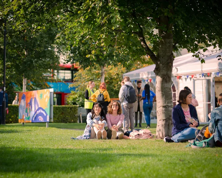 Students sitting on grass at campus green
