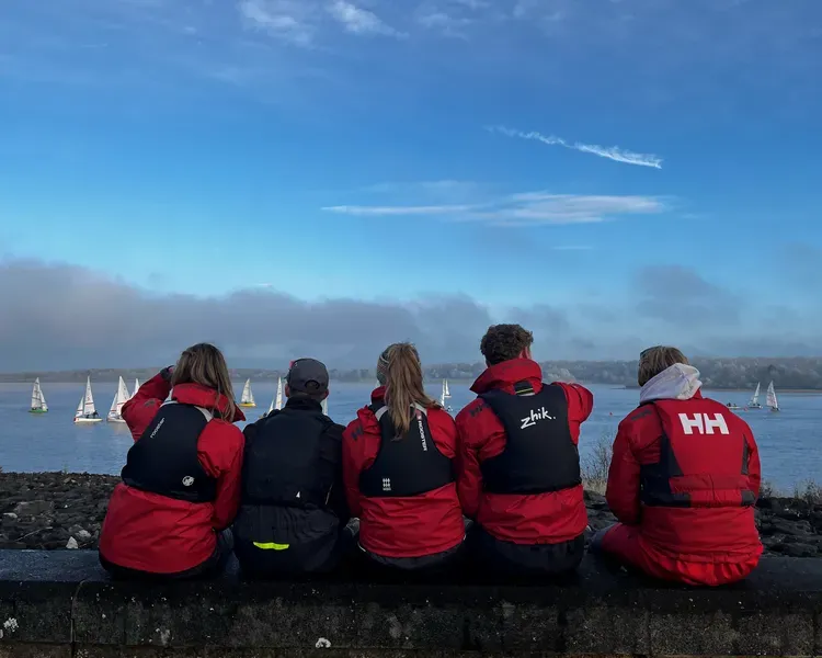 Students from the university sailing club sitting on a wall looking out over the River Tay