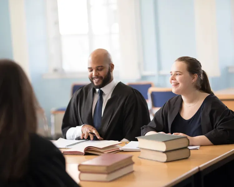 Law students having a meeting at a table with books on it. 