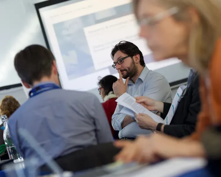 Students studying with laptops in a seminar room with slides projected to the side