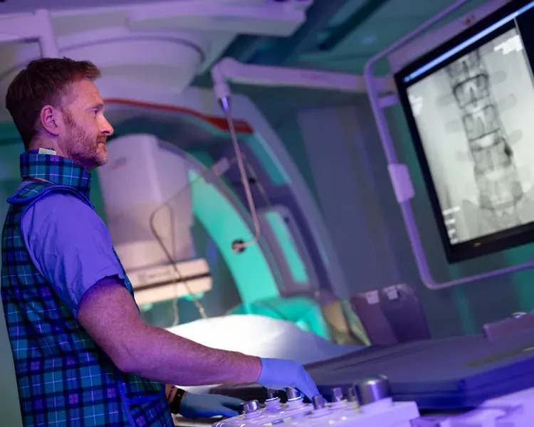 A man in a plaid shirt focused on a computer screen.