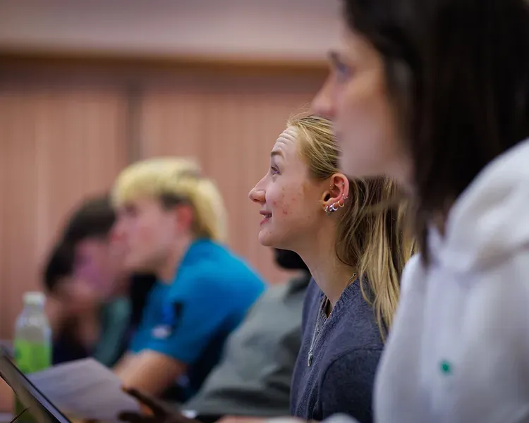 Students sitting in a lecture theatre looking up at the projection screen