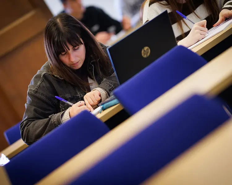 A student taking notes while in a lecture