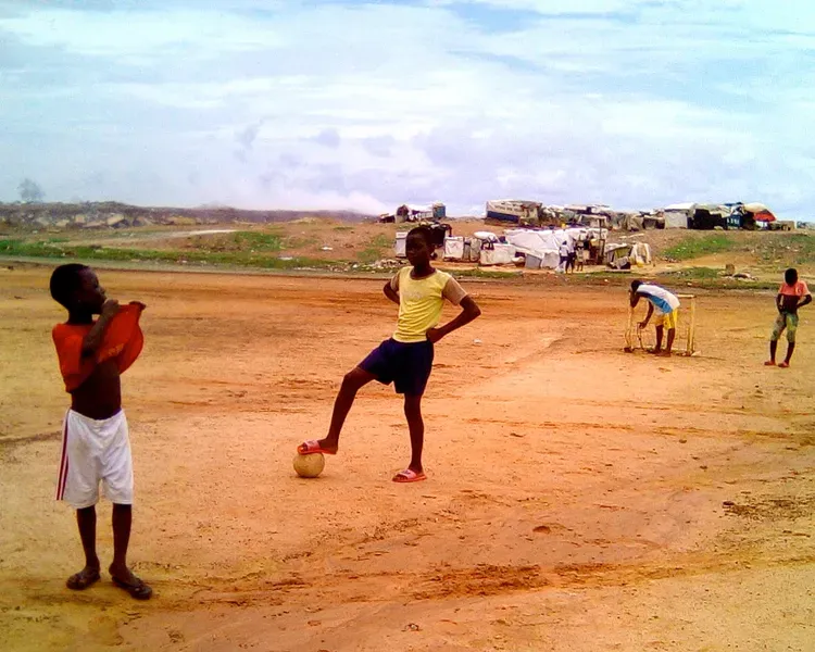 African youths playing football on red dirt area