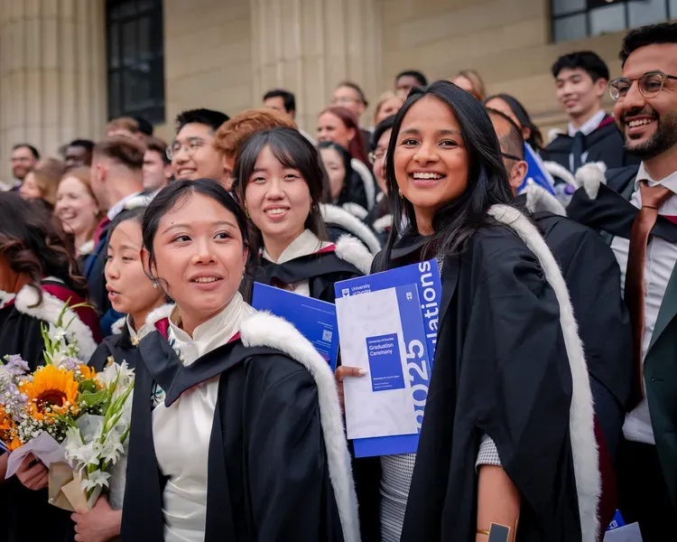 A group of graduates of the University of Dundee stand on the steps of the Caird Hall