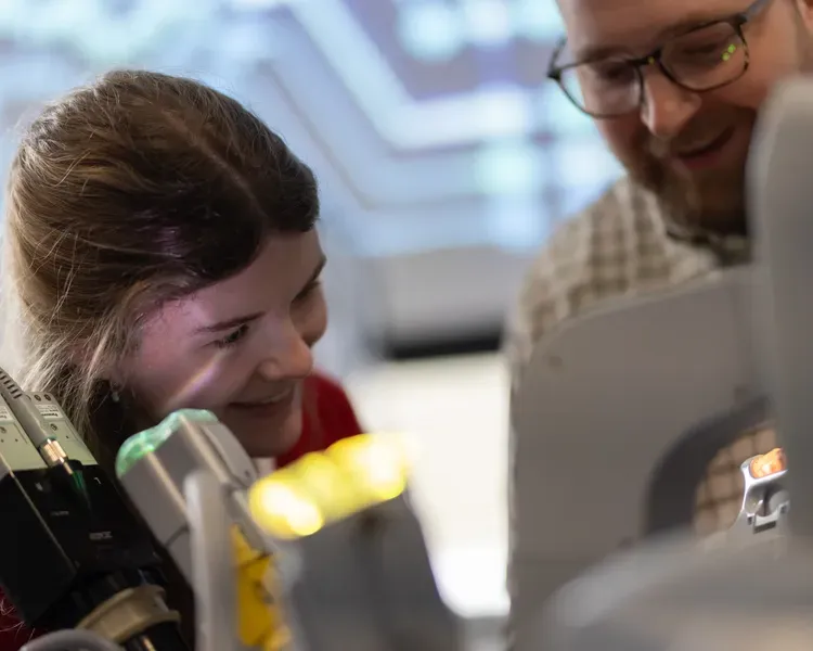 Two people are looking down and smiling at some apparatus 