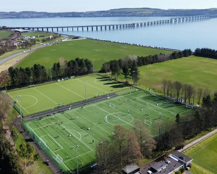 An Aerial view of playing fields beside the River Tay with the rail bridge and the road bridge in the distance.