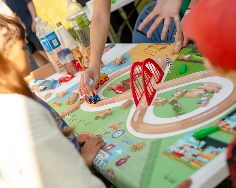 A board game of a town with children moving cars along a road