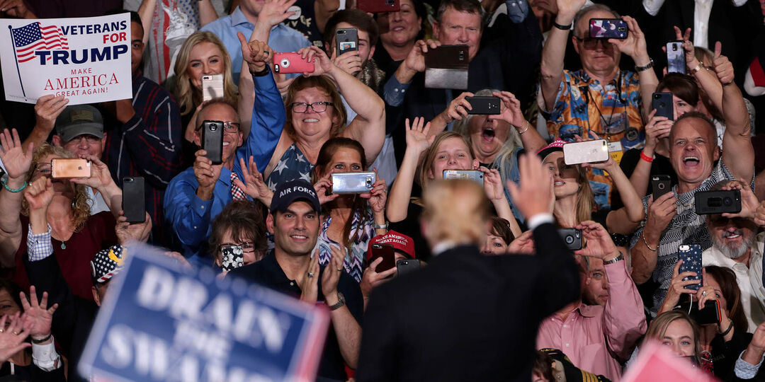 Donald Trump out of focus from behind waving to an in-focus crowd