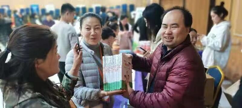 3 people holding a book