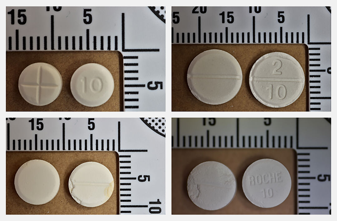 a photograph of a series of small round white and off-white tablets placed against rulers to show their size (between 7mm and 10mm approximately)