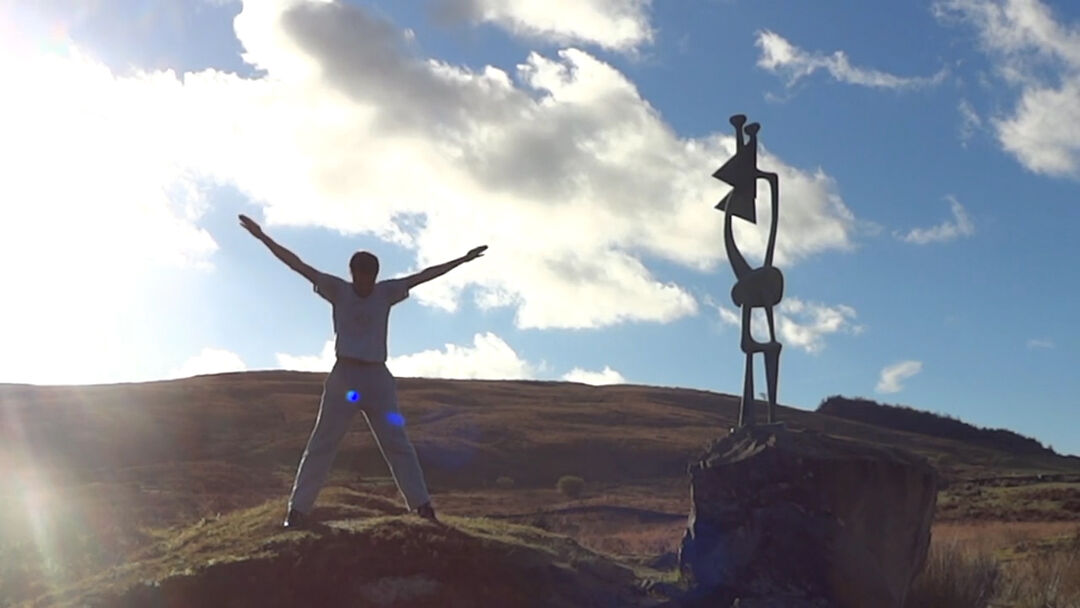 man with outstretched arms on hill