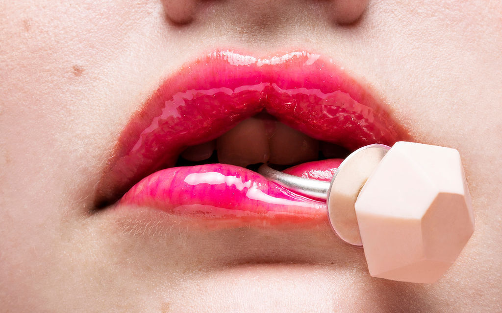 Close up of person's lips holding a ceramic ring piece with a large pastel pink hexagonal decoration