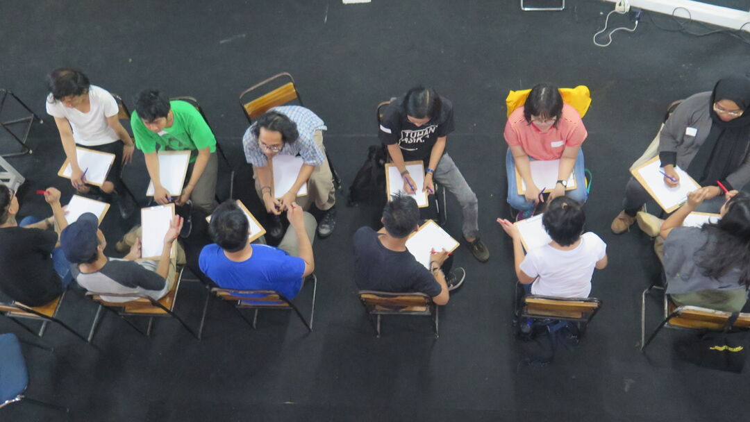 A view from above a row of people sitting in chairs on a black floor