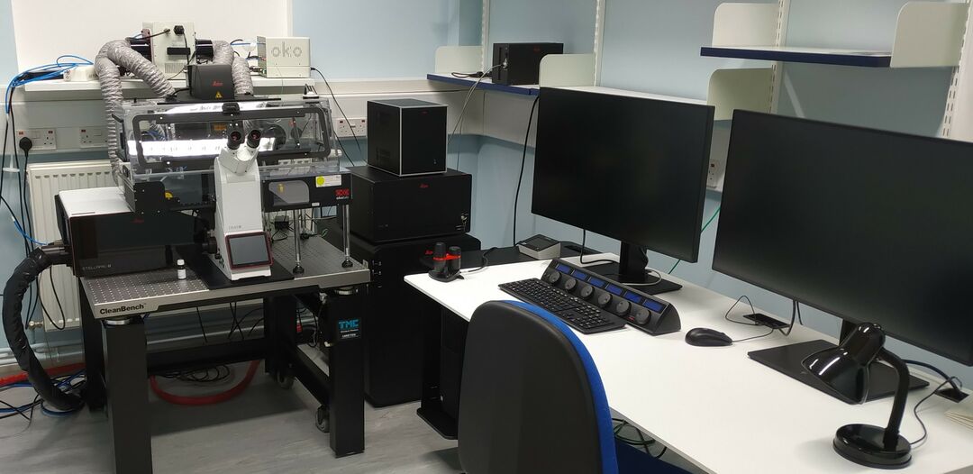 large microscope next to two computer screens