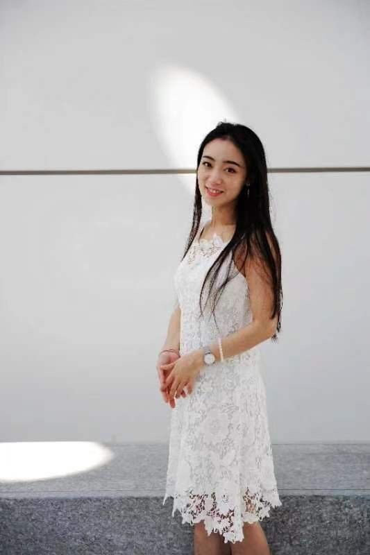 Portrait of Jacqueline Wang in a white dress, against a white wall.