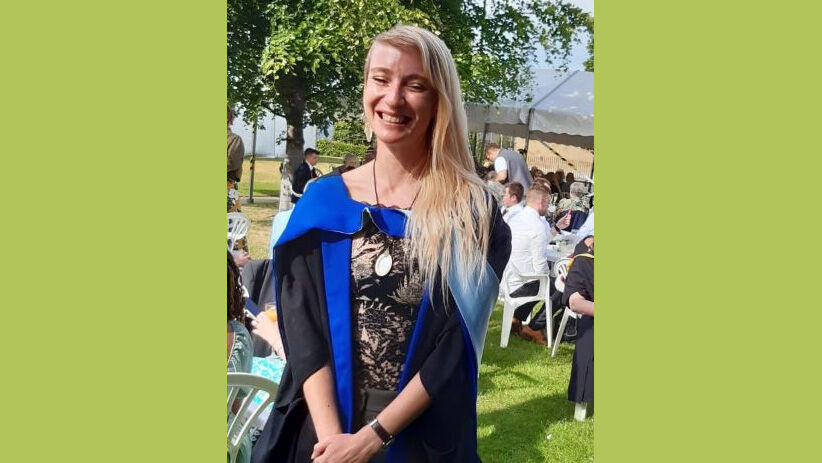 Fiona in graduation robes on campus green