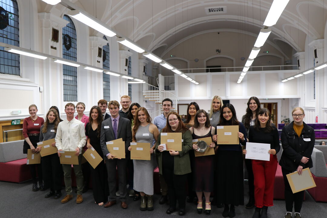 A group of Law School award winners holding their awards in the Law Library