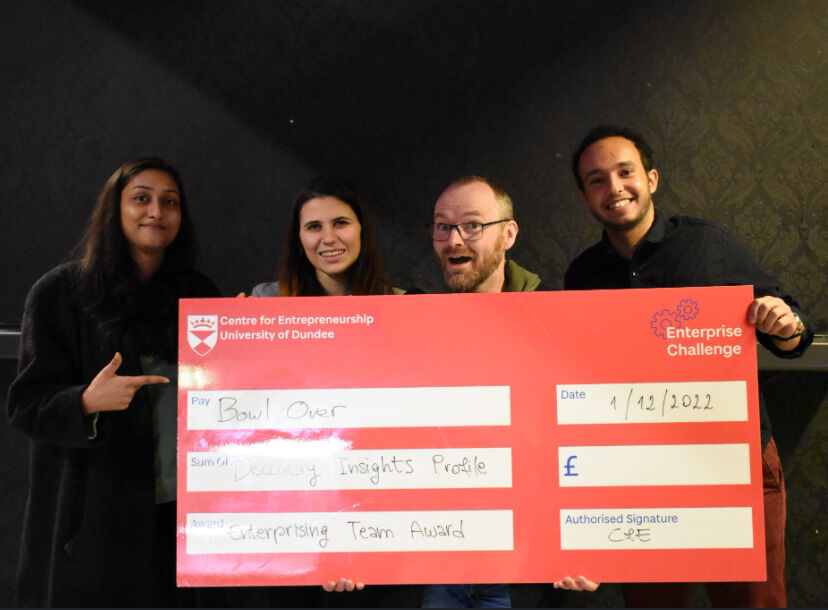 Four people holding an oversized cheque for winning and award for Enterprise Challenge competition