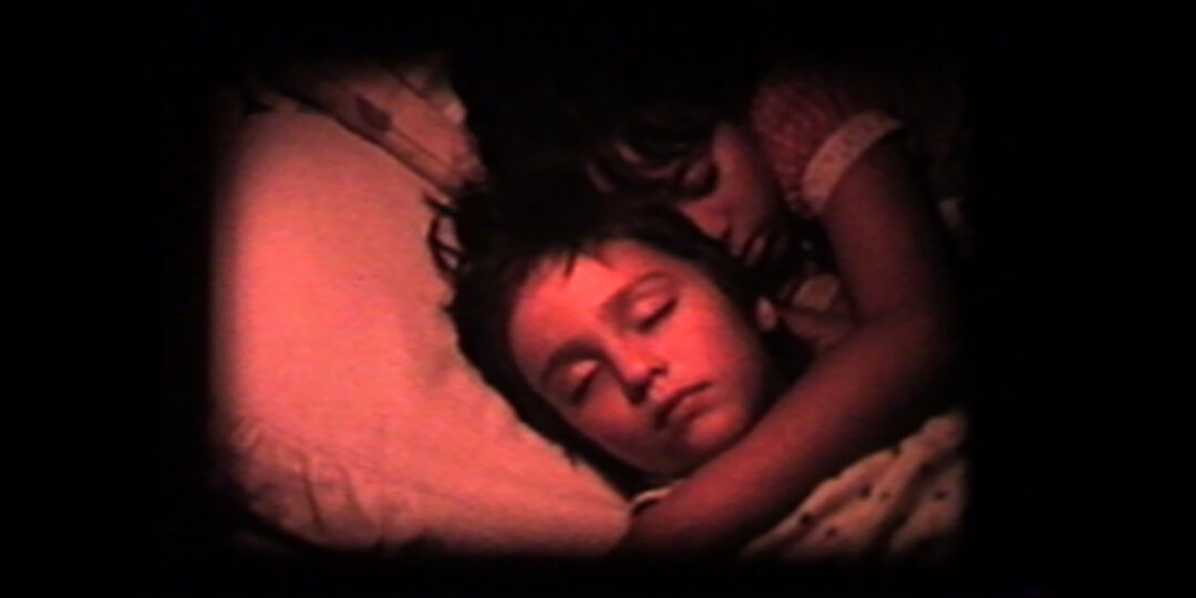 Two sleeping children hugging laying down on a pillow. The shot is in red.