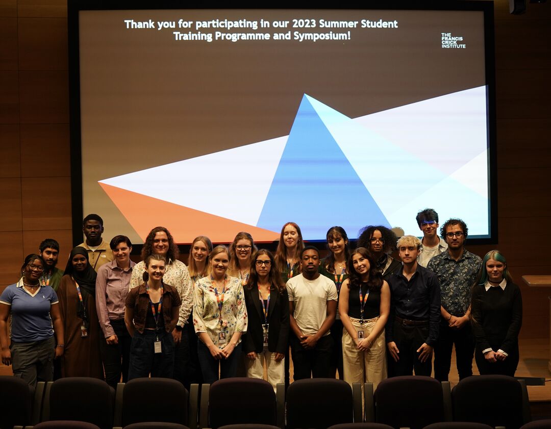 A group stands in front of a large screen.