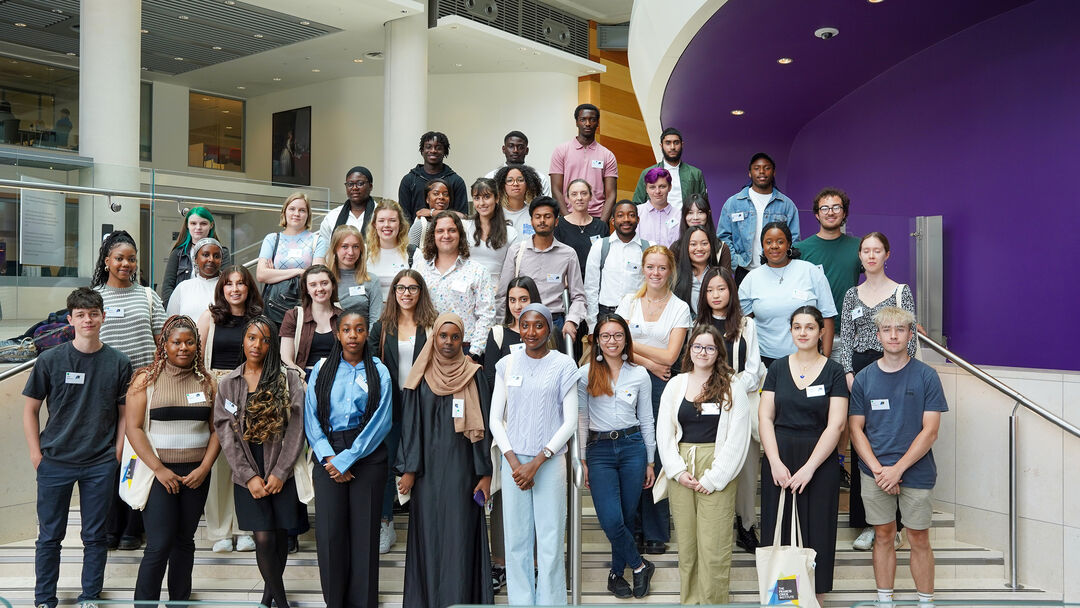 A group of people stand on a set of stairs, with their hands clasped in front of them.