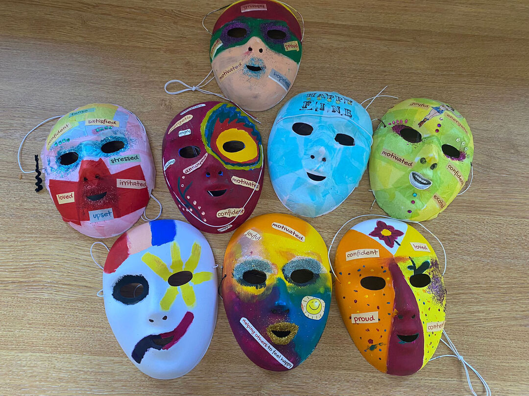 A selection of face masks painted in bright colours with stickers of positive statements 