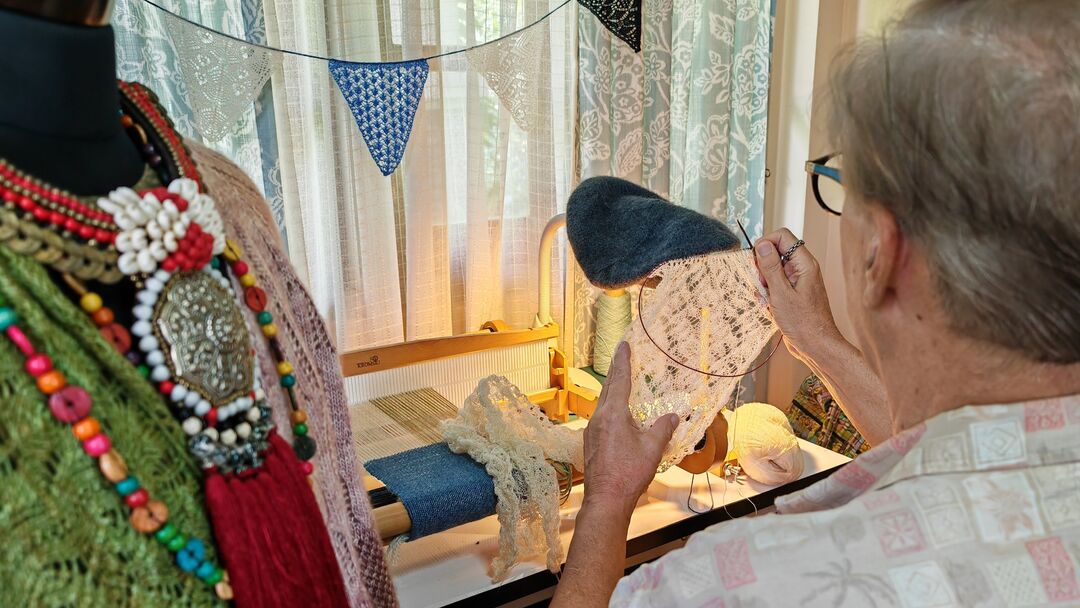 shot from behind of man sewing, close up of what he is making with materials around him