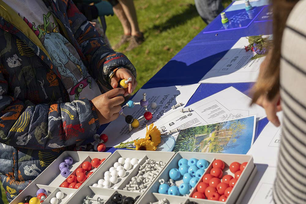 A close-up of hands making plastic molecules using plastic atoms and bonds.
